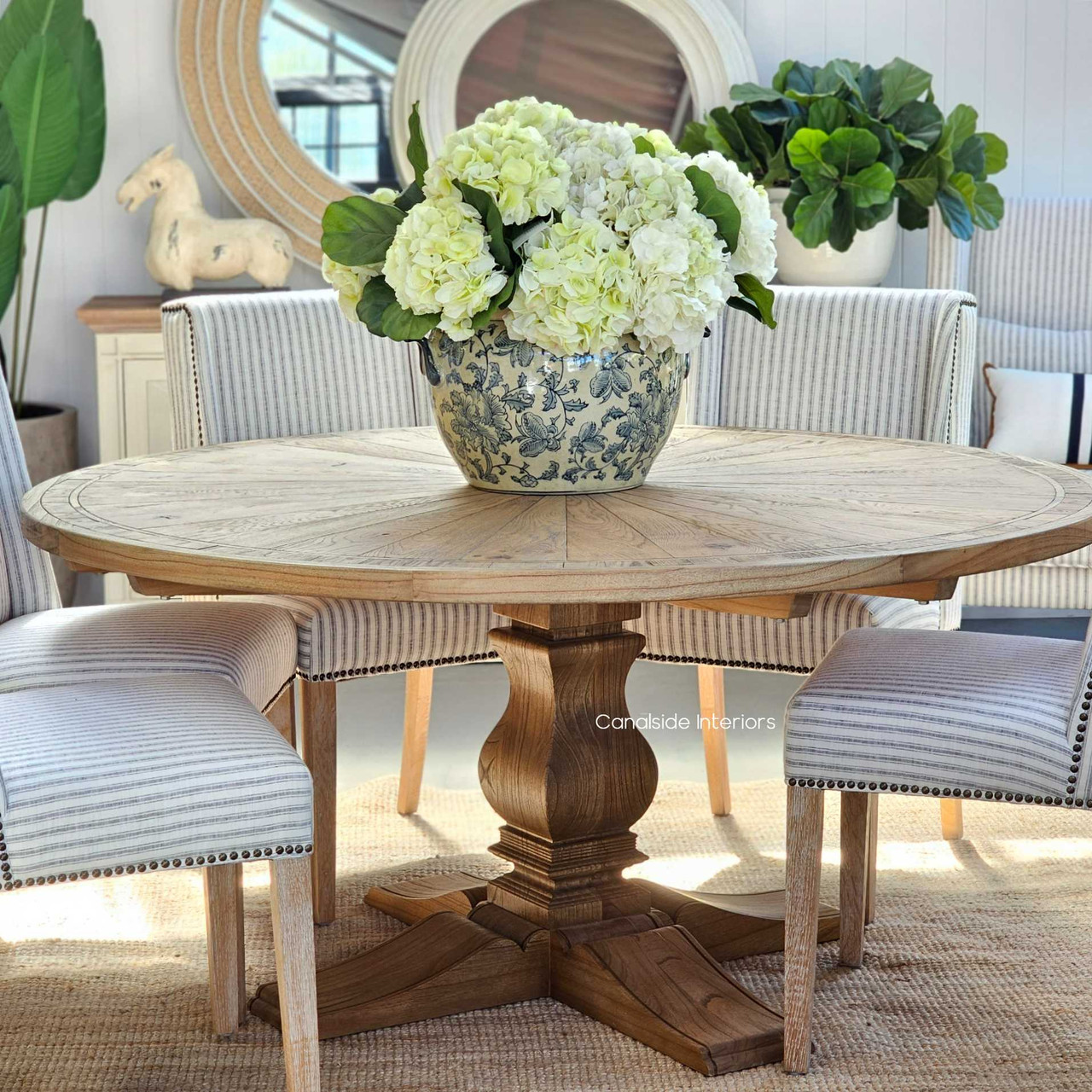 The circular Danbury Oak Parquetry Table is a testament to fine craftsmanship, its weathered oak grain and classic pedestal offering a warm, inviting dining experience - Canalside Interiors Sydney.