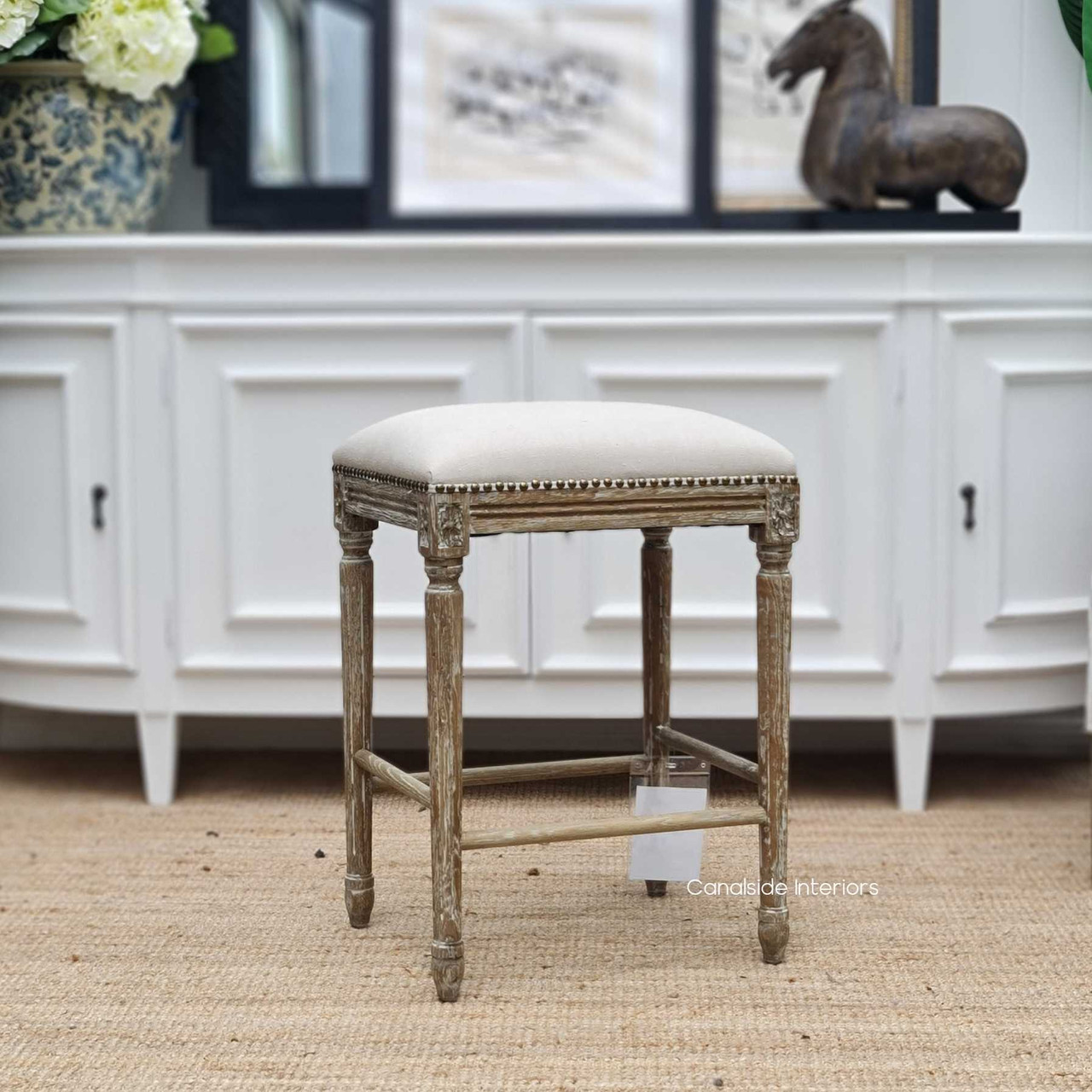 Front view of the Caylee Kitchen Stool, showcasing its classical cream linen upholstery that complements any modern kitchen island