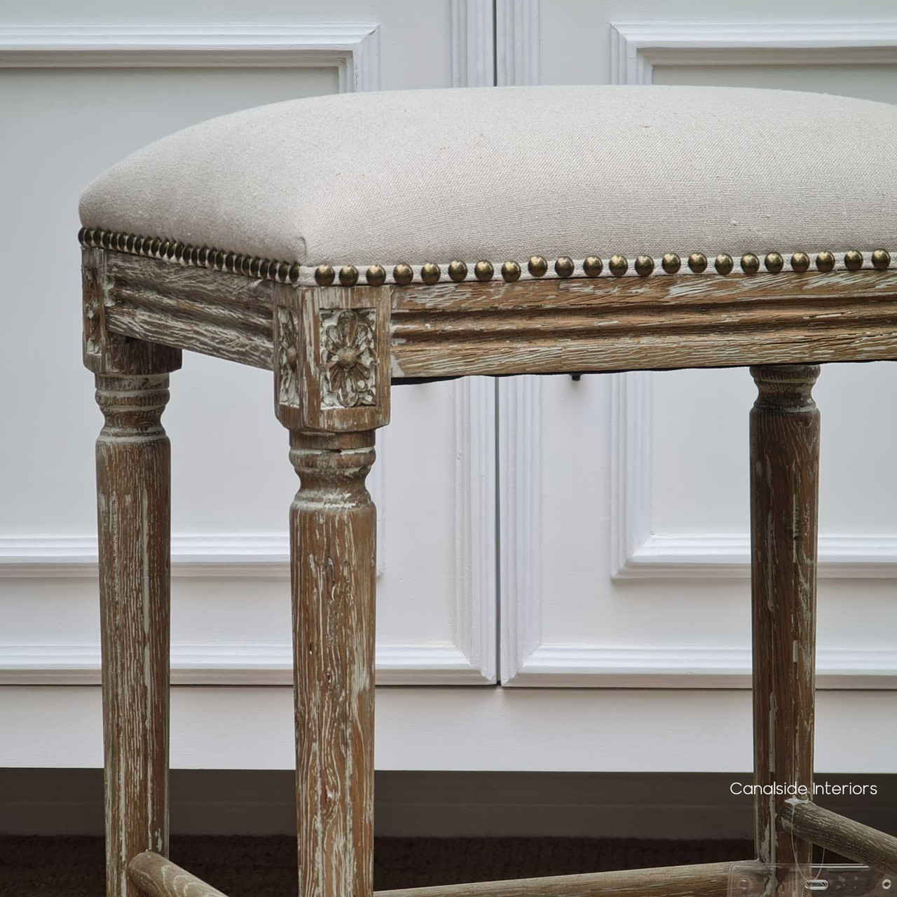 The cream linen of the Caylee Stool provides a subtle yet luxurious seating option, versatile for both bedroom and living room setting