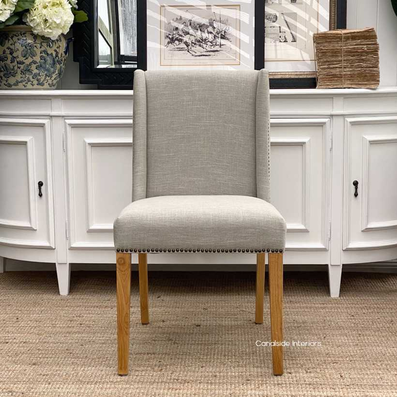 View of the Leclerc chair showcasing the winged back design and the perfect symmetry of brass studs, emphasizing the chair's refined aesthetics