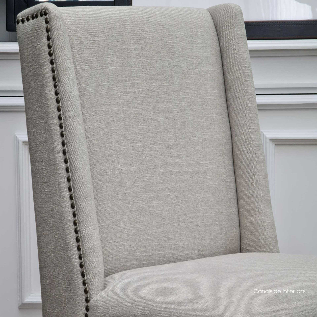 Side view of the Leclerc Dining Chair, emphasizing the classic winged back design and the natural beauty of oak legs in a well-lit dining setting.