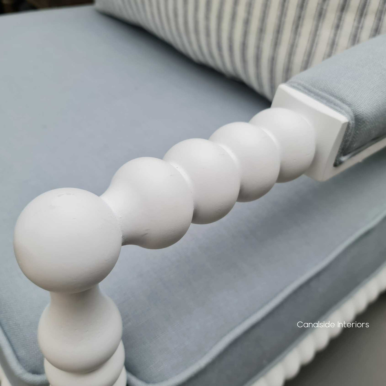 Detail shot of the corbeled bobbin arm and pastel blue linen blend upholstery, showcasing the soft texture and inviting color that adds charm to any room.