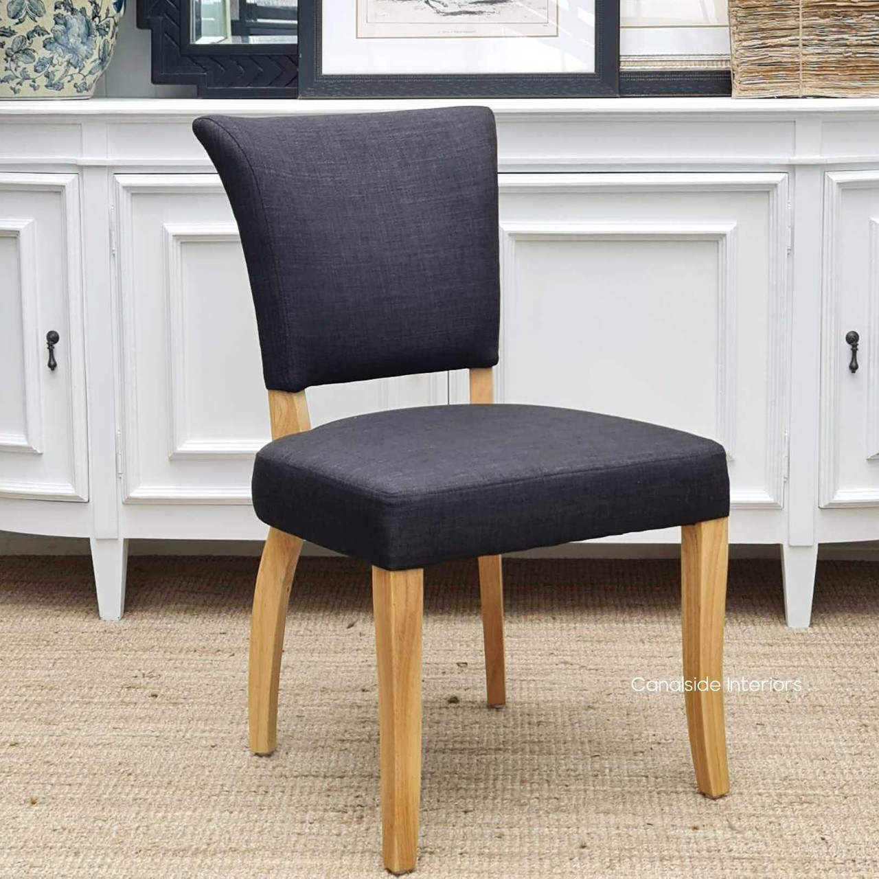 Side profile emphasizing the chair's curved hardwood legs in a distressed natural finish, adding a touch of rustic charm to its contemporary design.