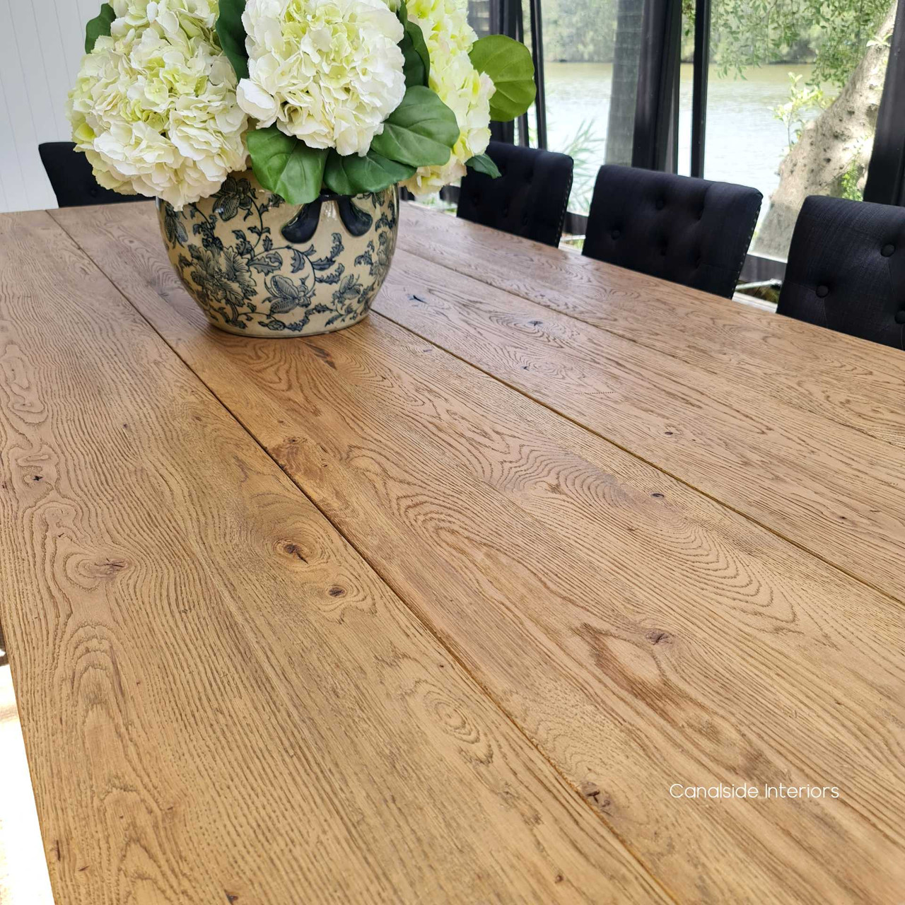 "Detail shot of the rustic timber top, a testament to the table's hearty construction and unparalleled craftsmanship.