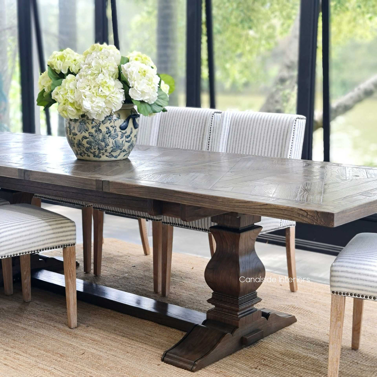 The captivating parquetry pattern of this extendable dining table offers timeless appeal, making it an impeccable choice for any Canalside Interiors coastal setting