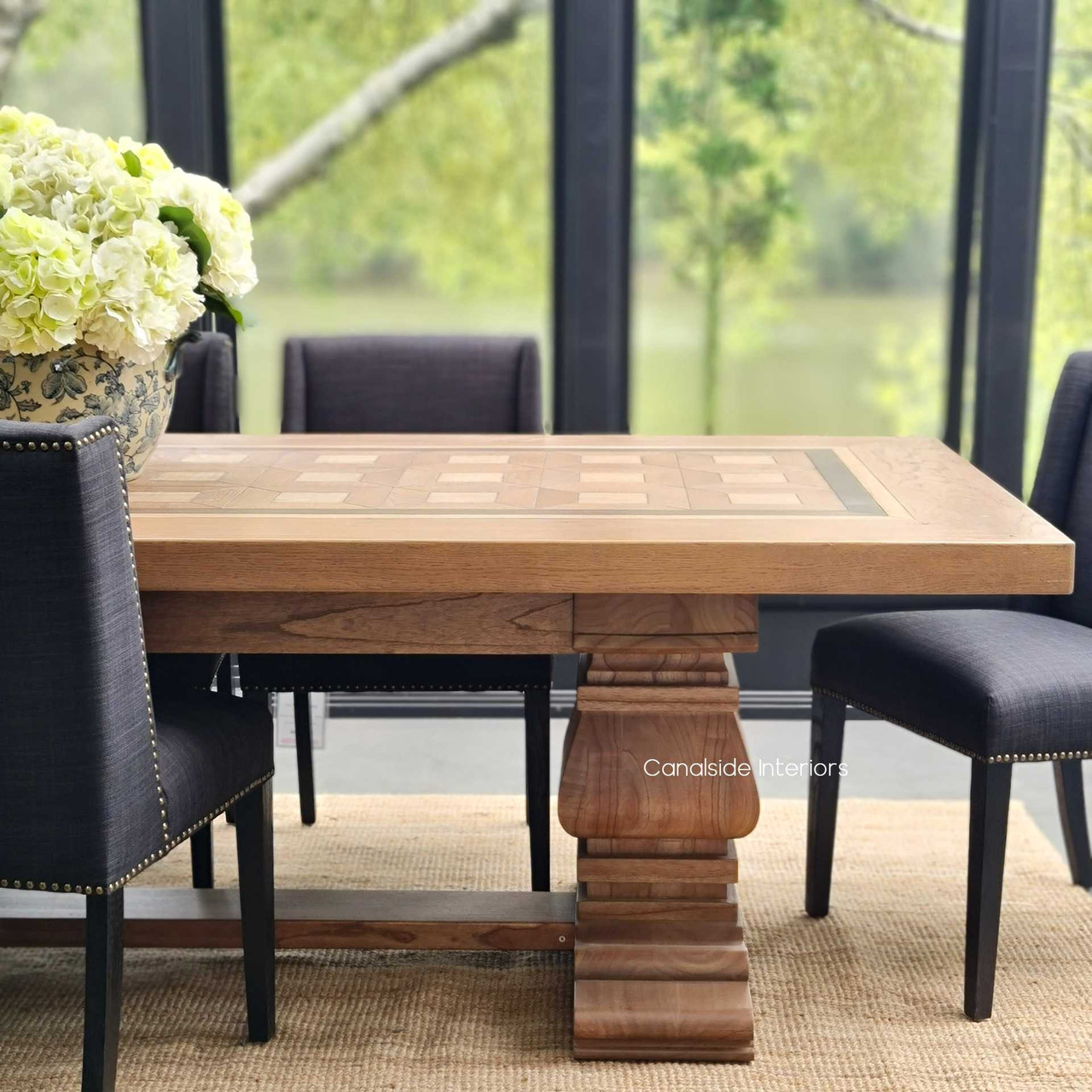 Angled shot of the Chambers Dining Table, showcasing the combination of American Oak and White Cedar in a spacious library setting.