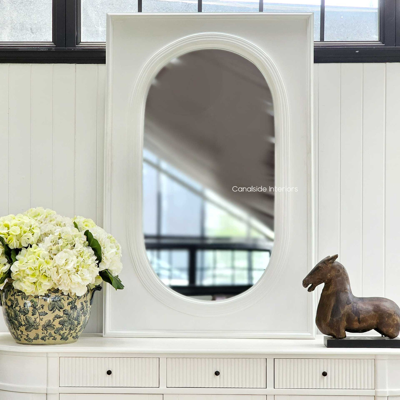 The Ovalis Mirror, with its distressed white finish, offers a timeless reflection for a refined library or home office space