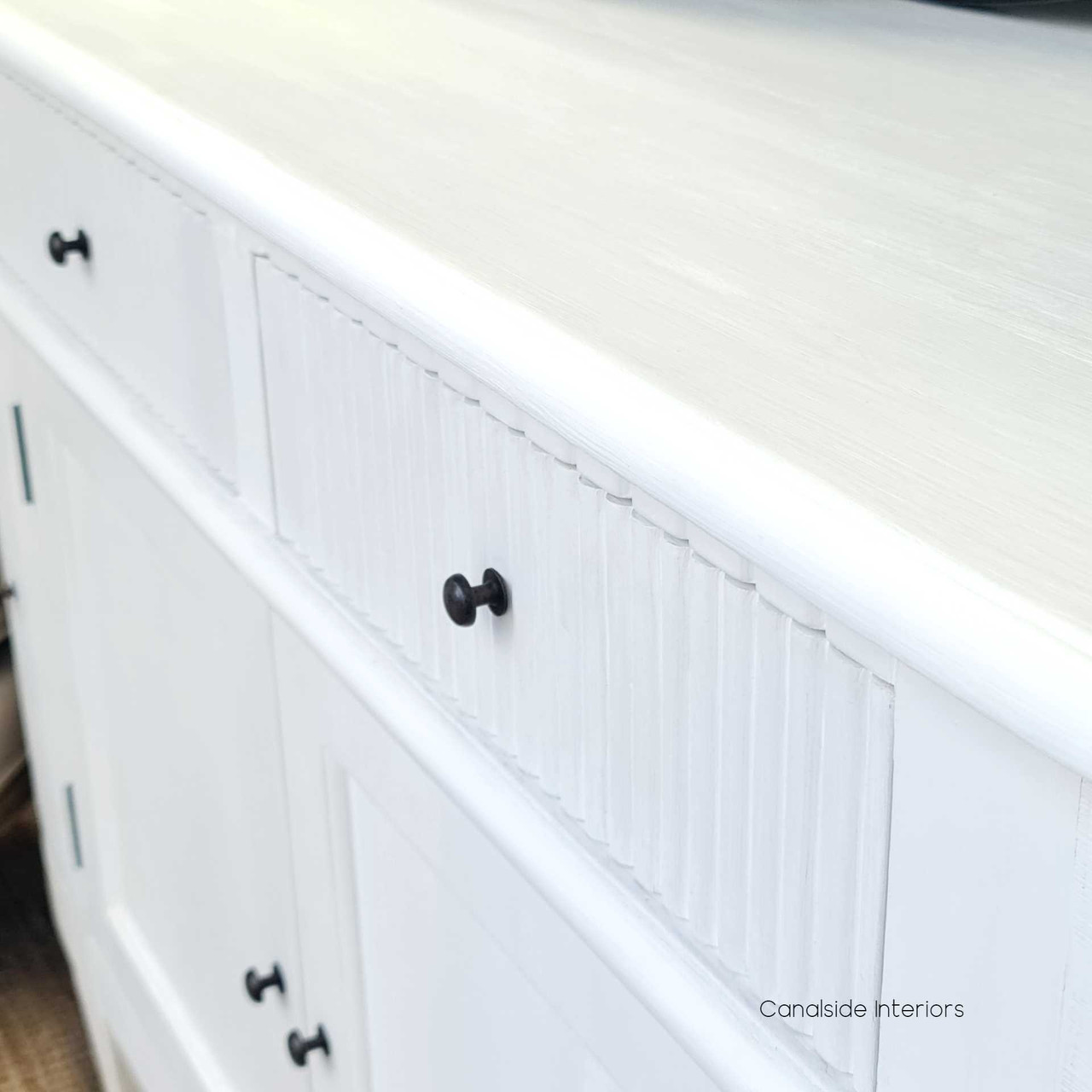 The French Louis Buffet Petite captured under natural light, emphasizing the beauty of its distressed white finish and elegant design.