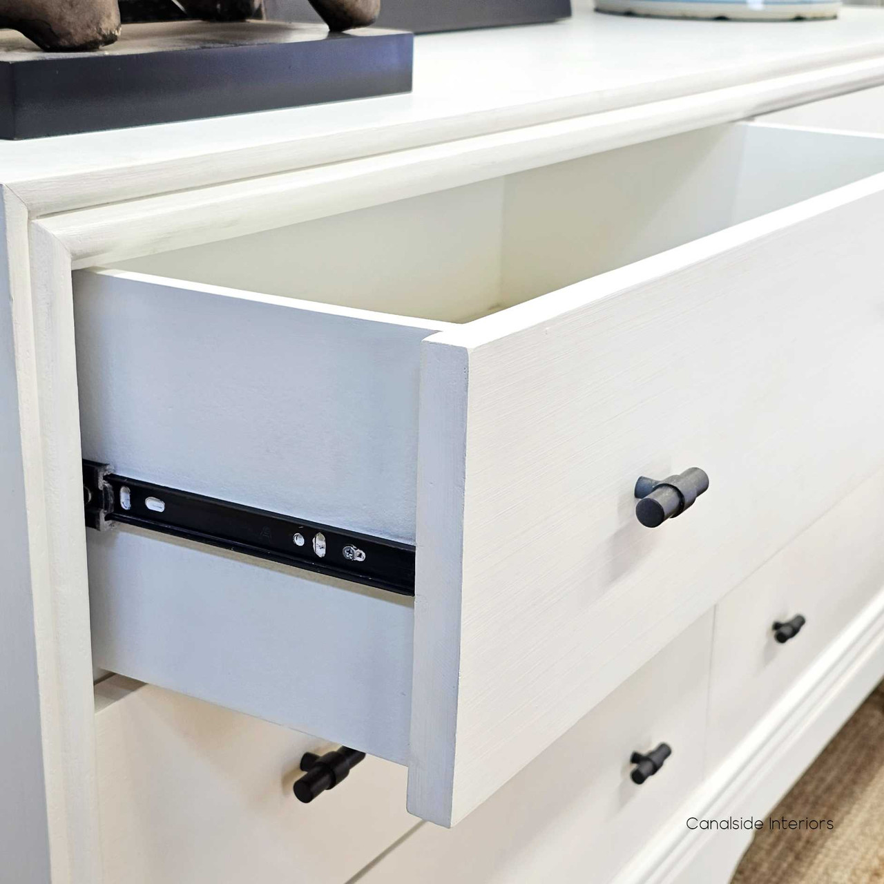 Detailed shot of the Camille Chestâ€™s metal runners, emphasizing smooth functionality in a classical bedroom setting