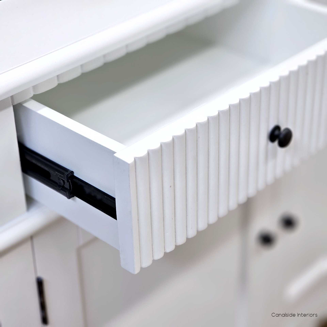 Close up view of the metal drawer runners of the Louis Curved Sideboard in white