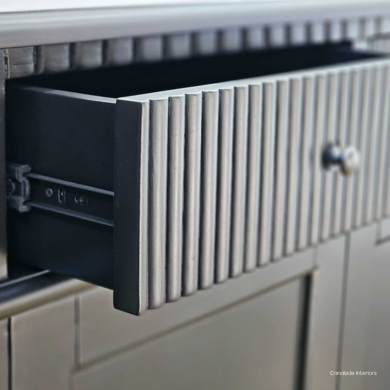 View of an open drawer in the Louis Curved Buffet, illustrating storage space and metal drawer runner.