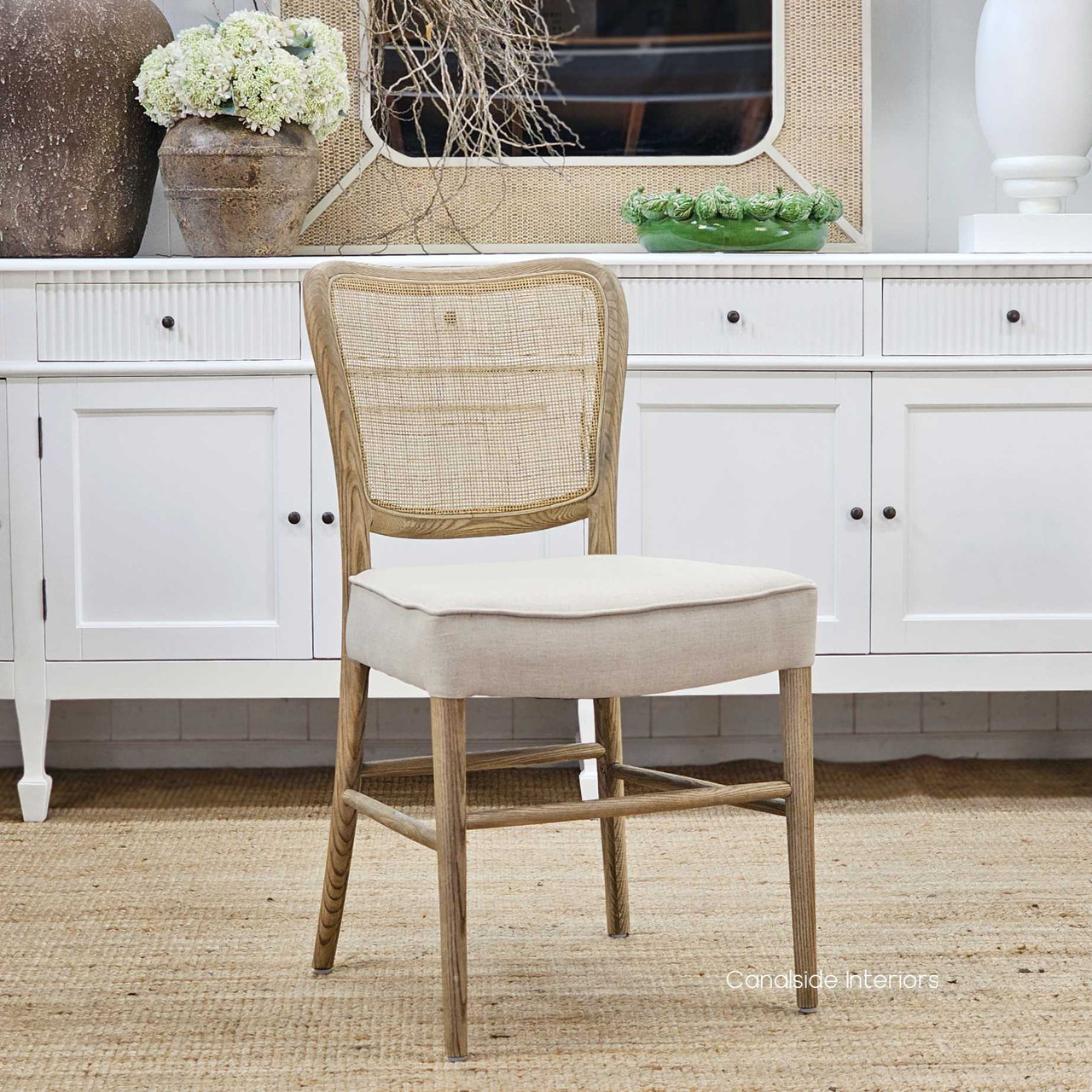 Angled front view of the Noda Oak Rattan Dining Chair, highlighting its elegant silhouette, natural wood tones, and intricate rattan weave.