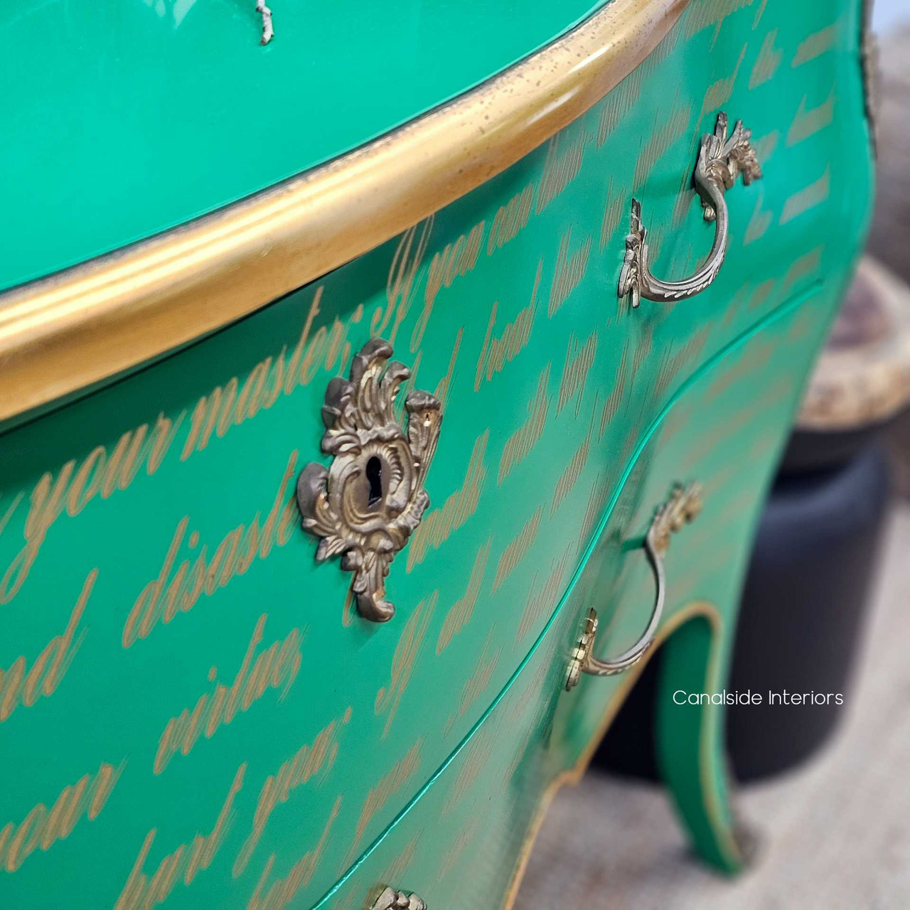 Detailed shot of the ornate drawer handles, revealing aged gold patina and floral-inspired carvings.