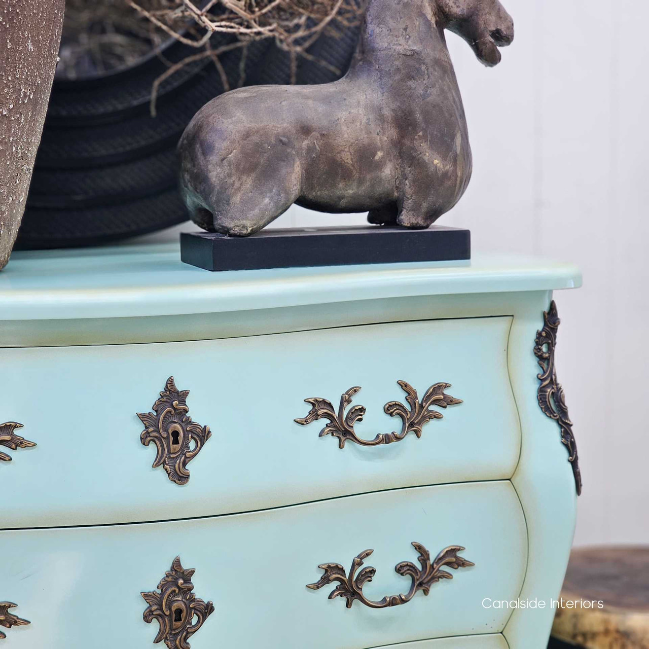 Three-quarter view styled with pottery and vintage accents, creating a relaxed, refined vignette.