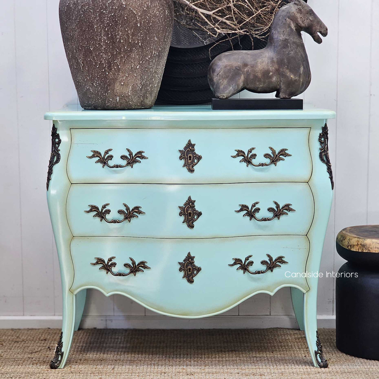 Front view of the Bretigny Commode Chest in distressed aqua, showcasing its bombe shape and ornate bronze hardware.
