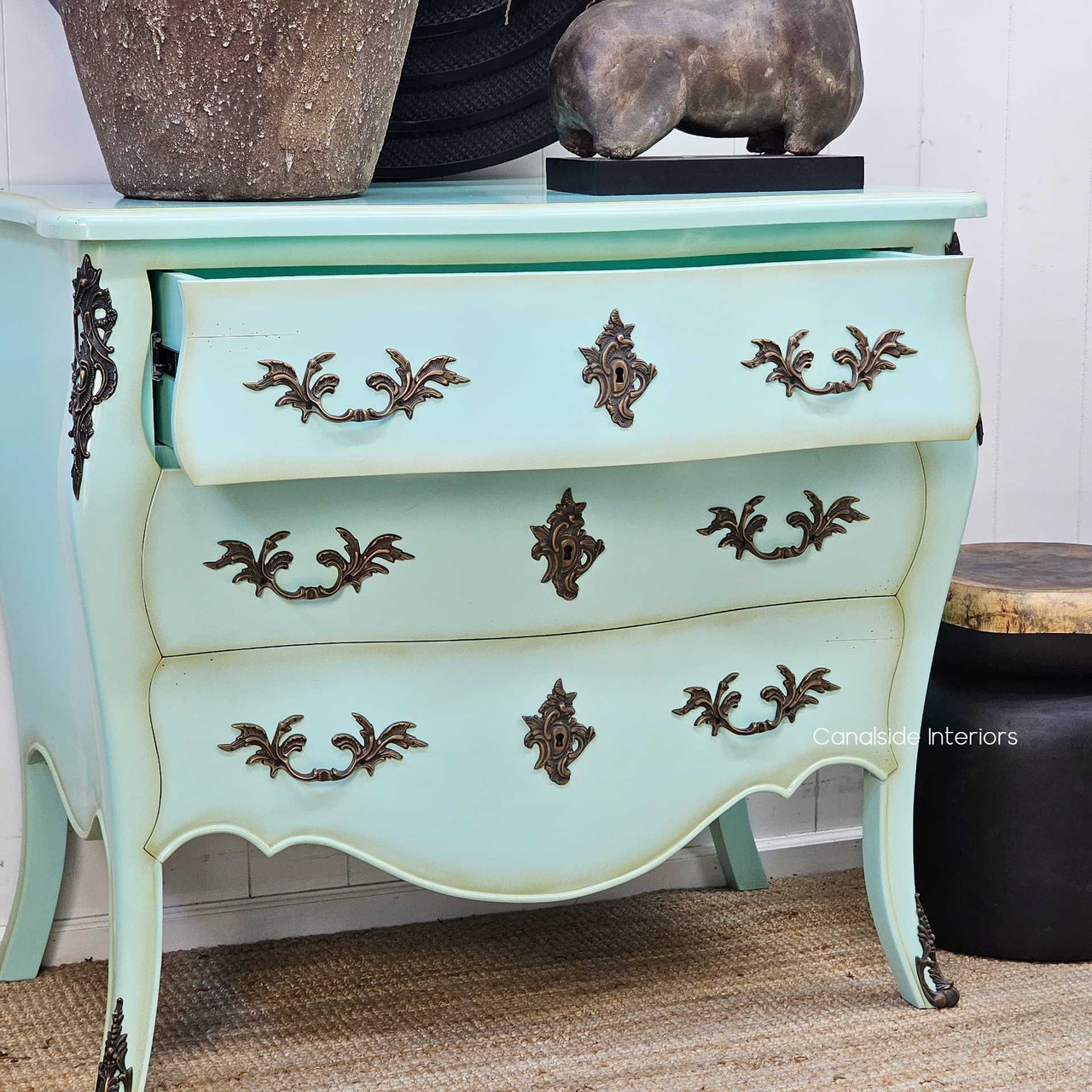 Angled view with drawer slightly open, showcasing storage function beneath its decorative façade.