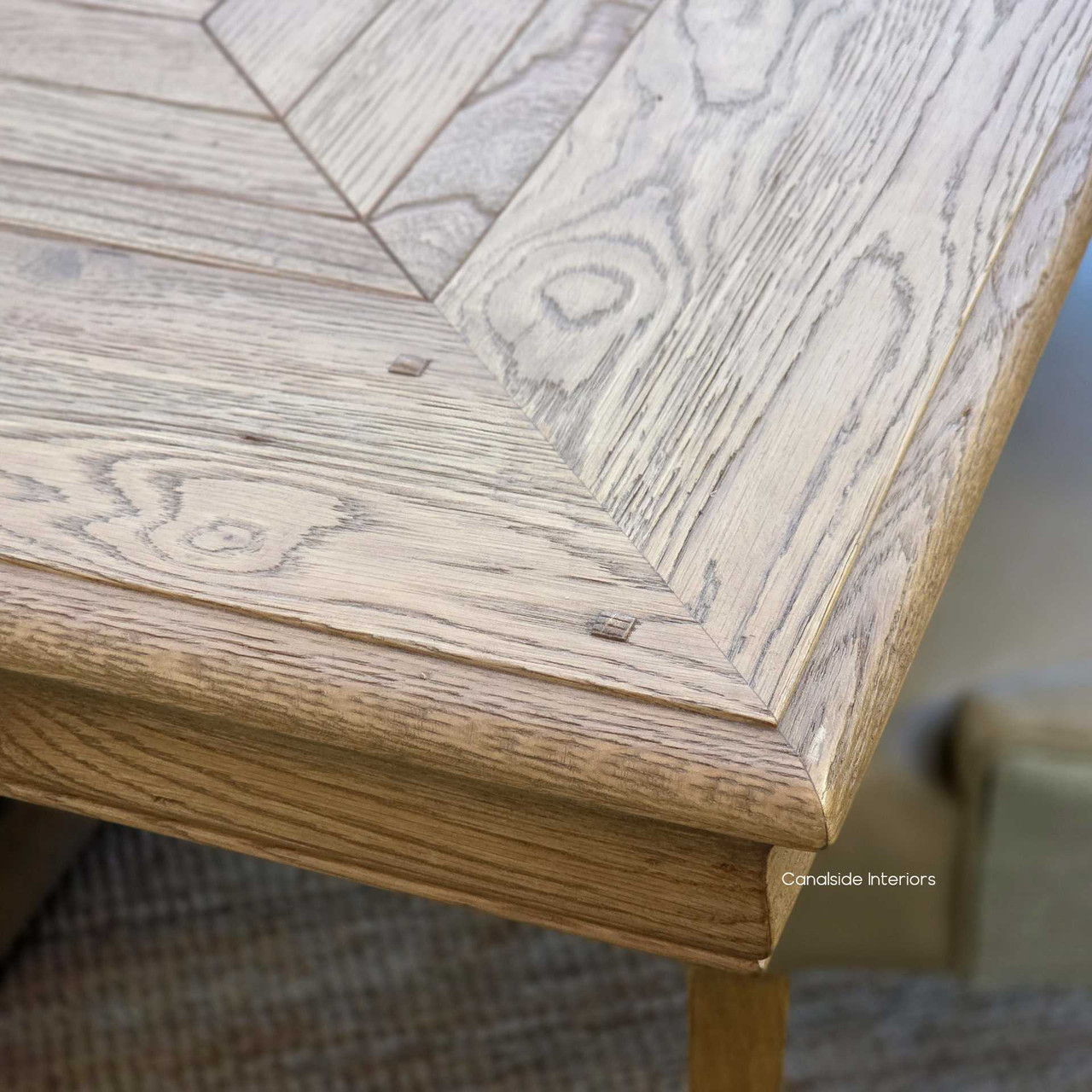 Close-up of carved geometric apron detailing on the Chesterton oak dining table.