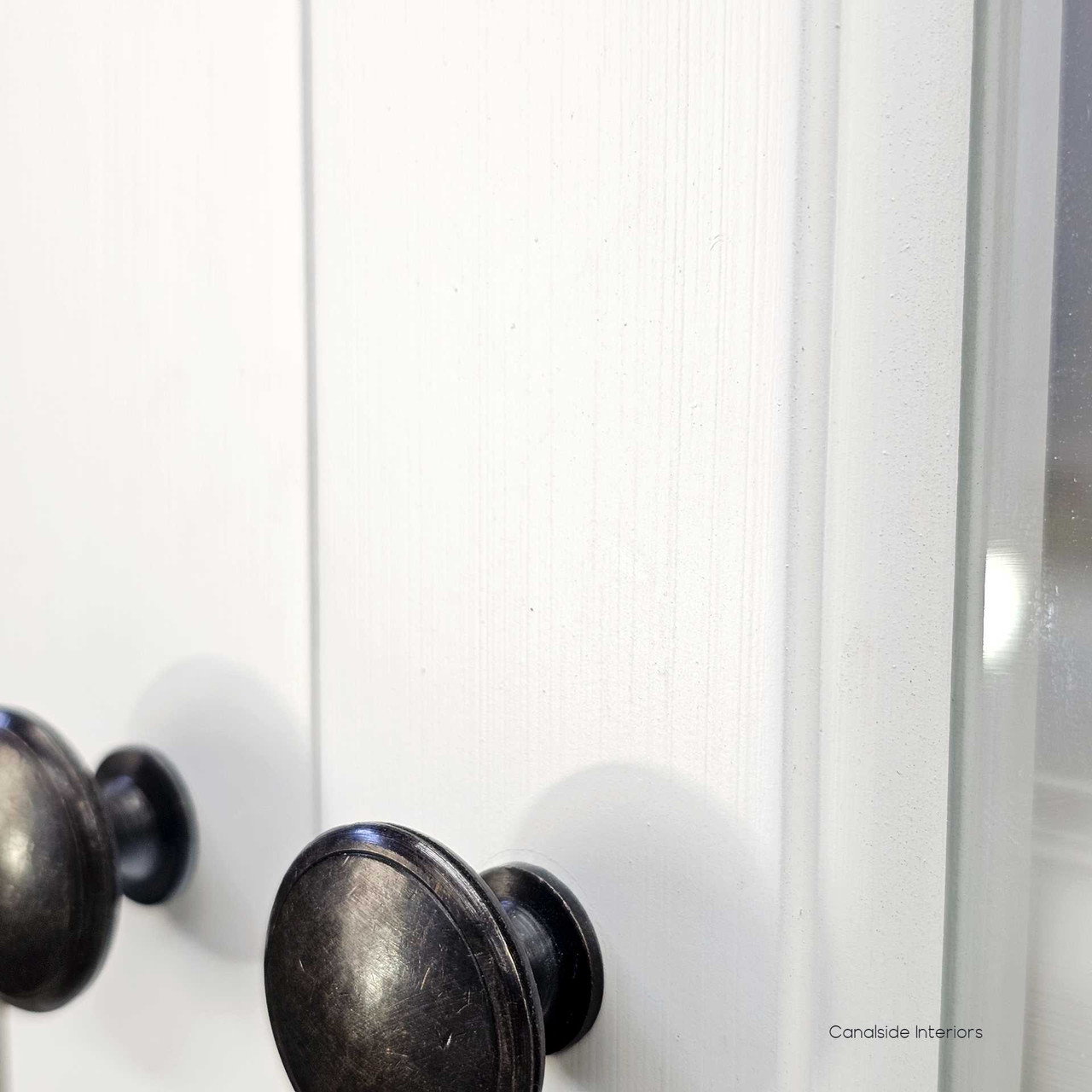 Close-up of the brass metal knobs on the white drawers, offering a clean contrast and timeless finishing touch
