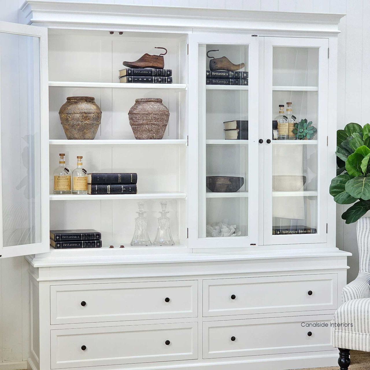 Shelves styled with neutral books, ceramics and greenery for a refined Hamptons look.