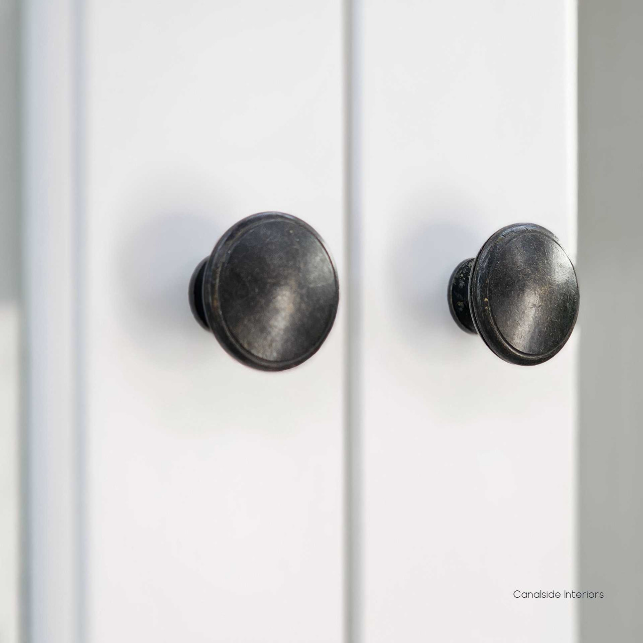 Close-up of the brass knobs on the upper doors, offering a refined contrast against the crisp white painted finish.