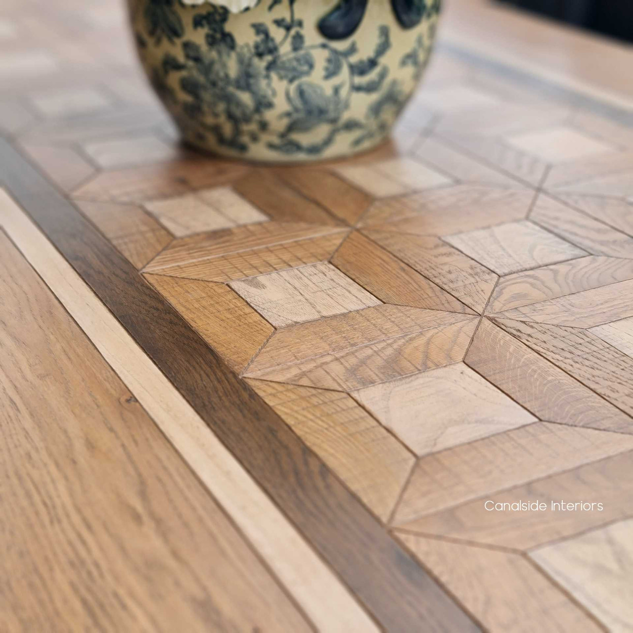 The Chambers Dining Table's top surface, a display of fine timbers and intricate parquetry, ready to enchant guests in a grand dining room