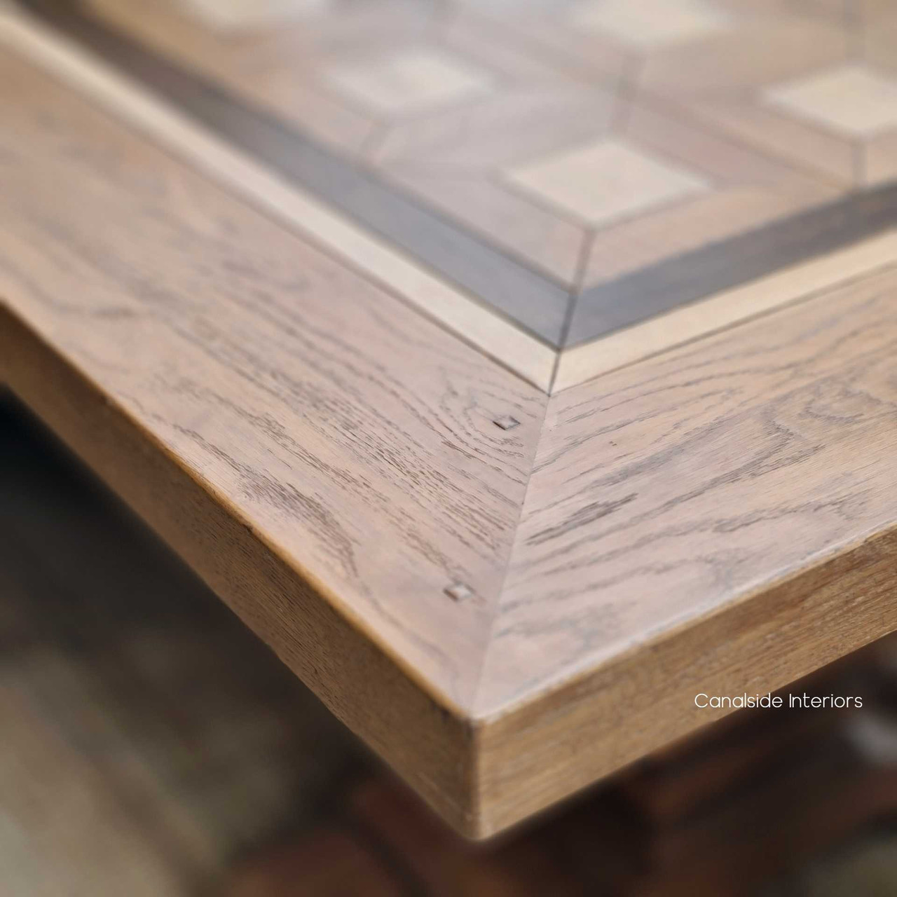 Artistic shot focusing on the Chambers Dining Table's edge, where the fine wood grains and parquetry inlay intersect.