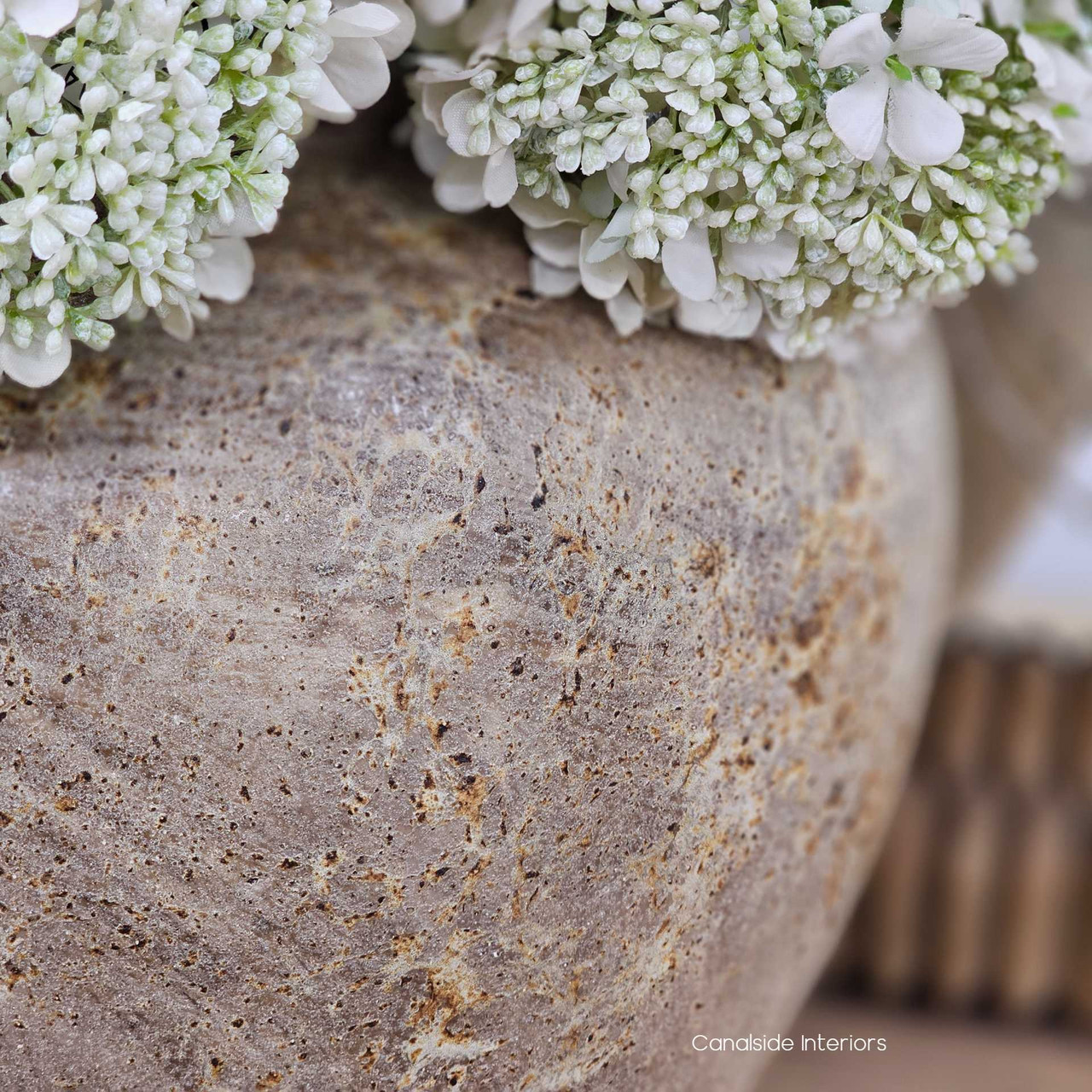 Close up view of the Noema terracotta vessel filled with dried flowers, ideal for organic shelf styling or console displays.