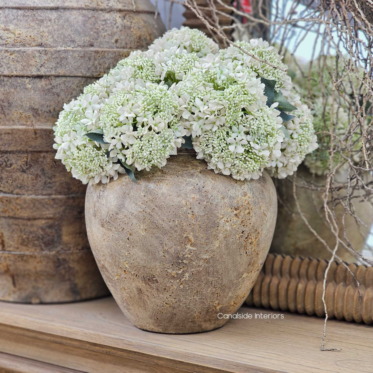 Noema clay pot styled with white faux florals, offering a natural contrast against its rustic finish.