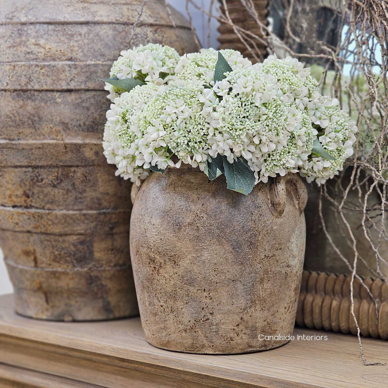 Sekar clay pot styled with white faux florals, offering an elegant contrast to its earthy tones.