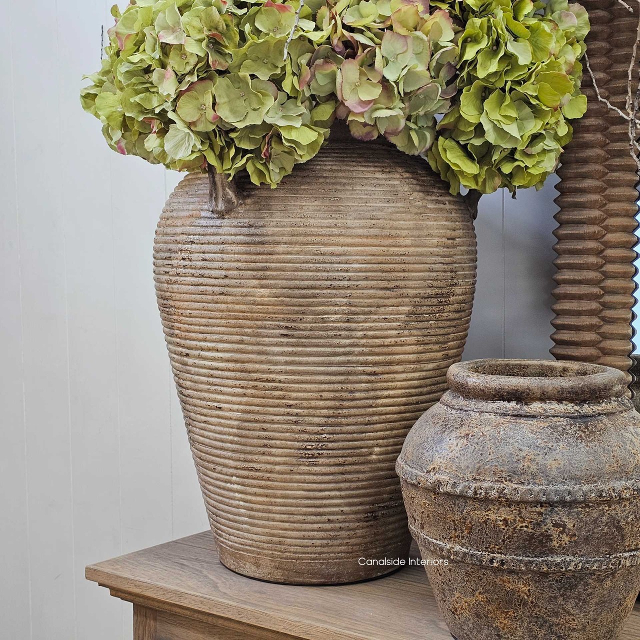 Lirien vessel paired with smaller pots in a neutral vignette, enhancing its bold, earthy presence.