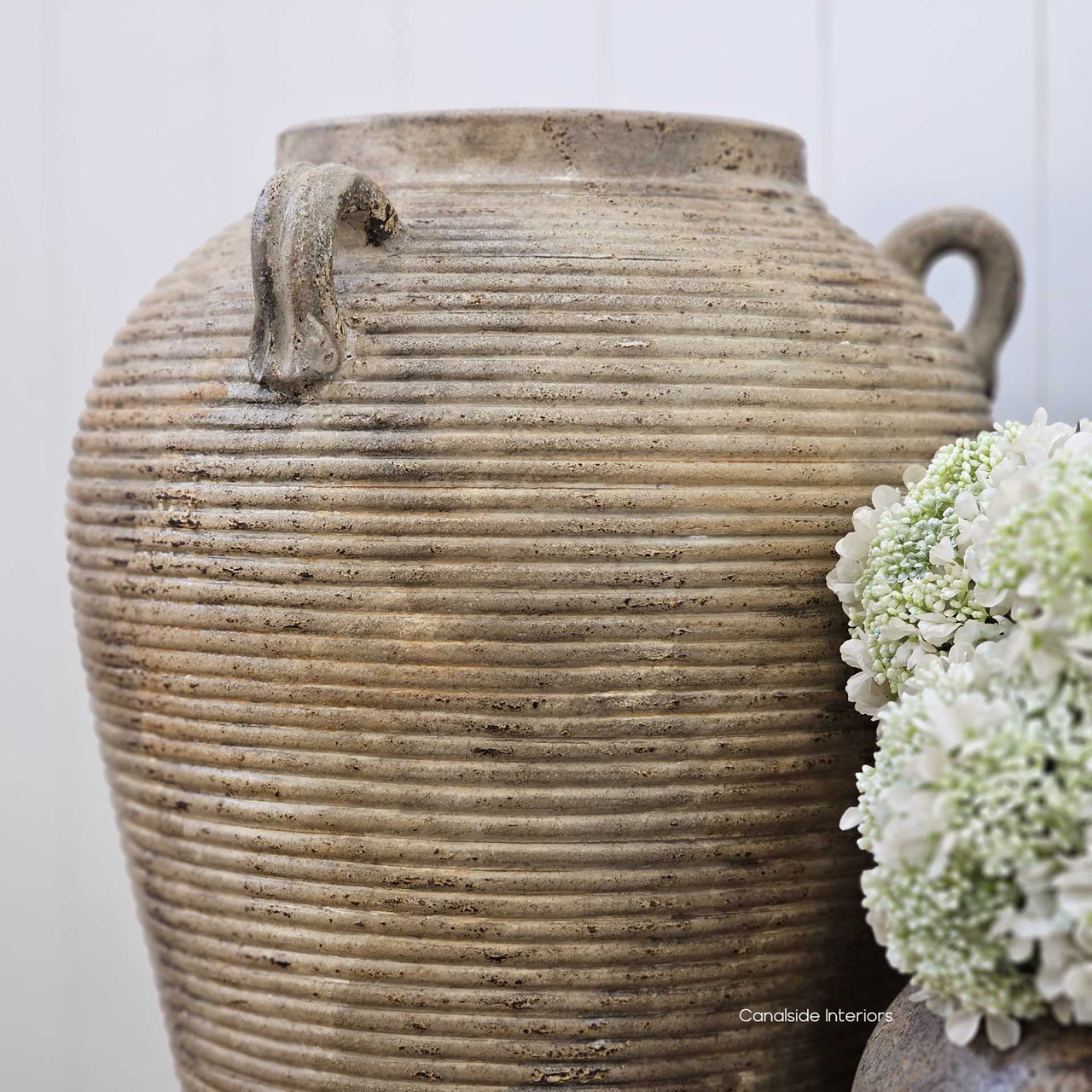 Angled shot of the Lirien vessel with light catching its ribbed surface, showcasing the natural depth and variation in the terracotta finish.