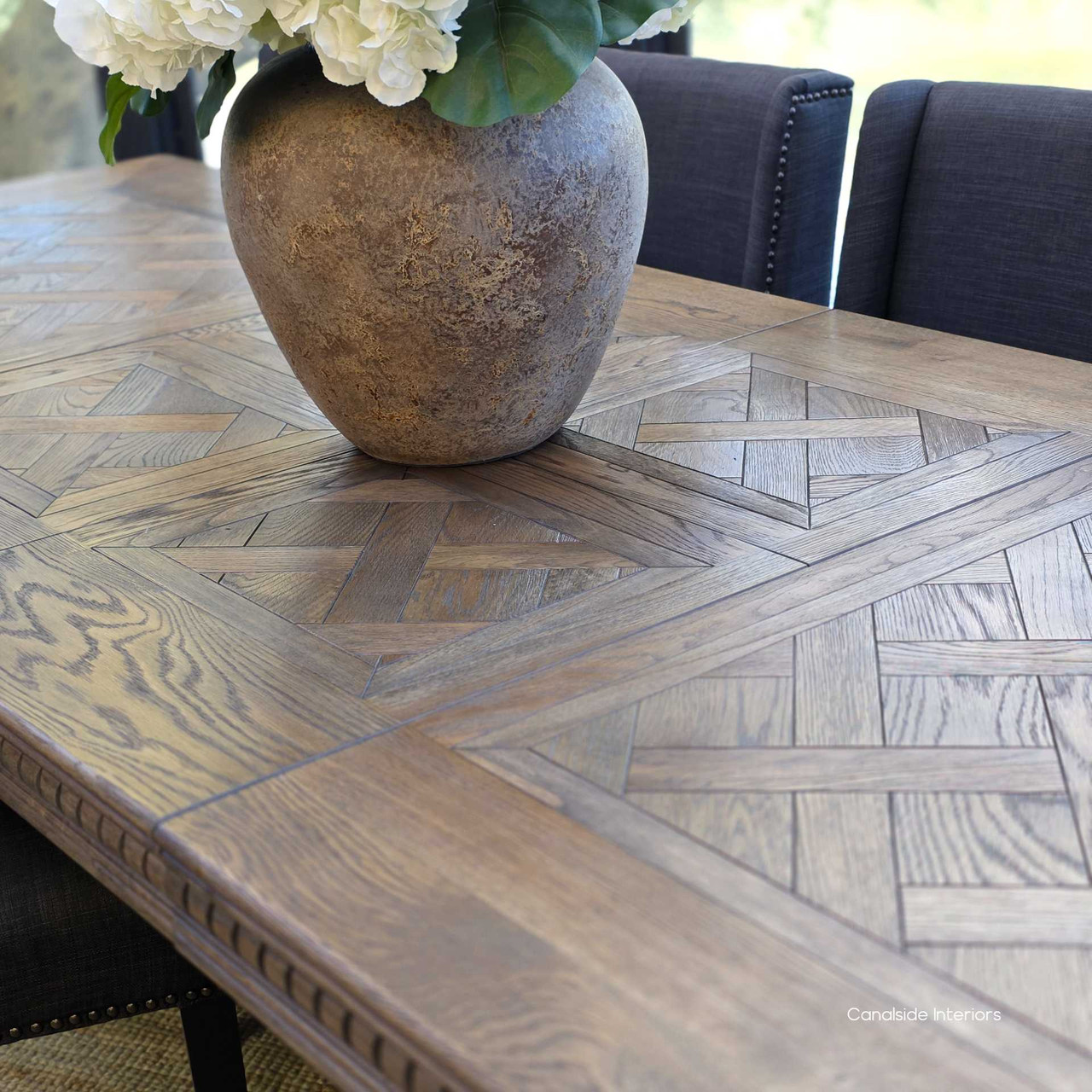 Oak parquetry dining table in Cigar with elegant carved detailing.