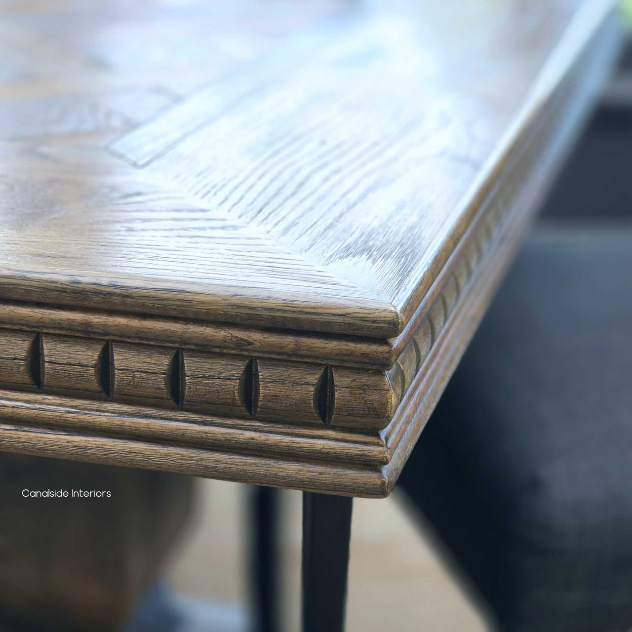 Detailed shot of carved geometric apron on the Berenson Cigar oak dining table.