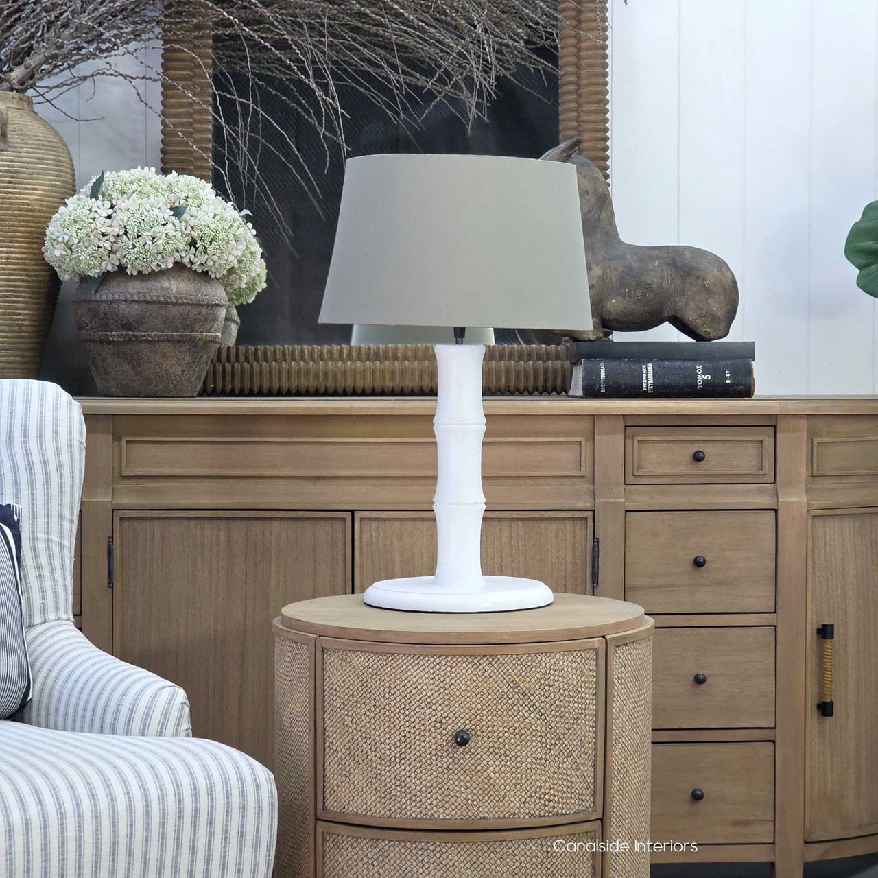 Distressed white bamboo lamp base with neutral taupe shade in neutral setting
