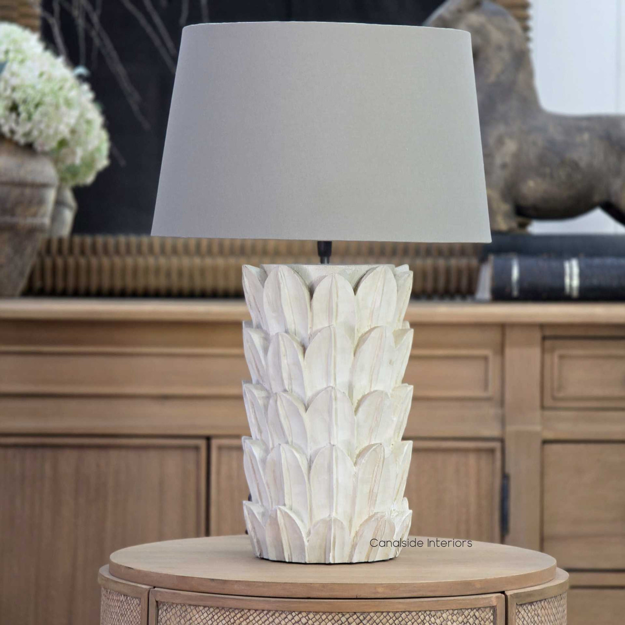 Foliole distressed white hand-carved wooden table lamp with taupe shade on round side table