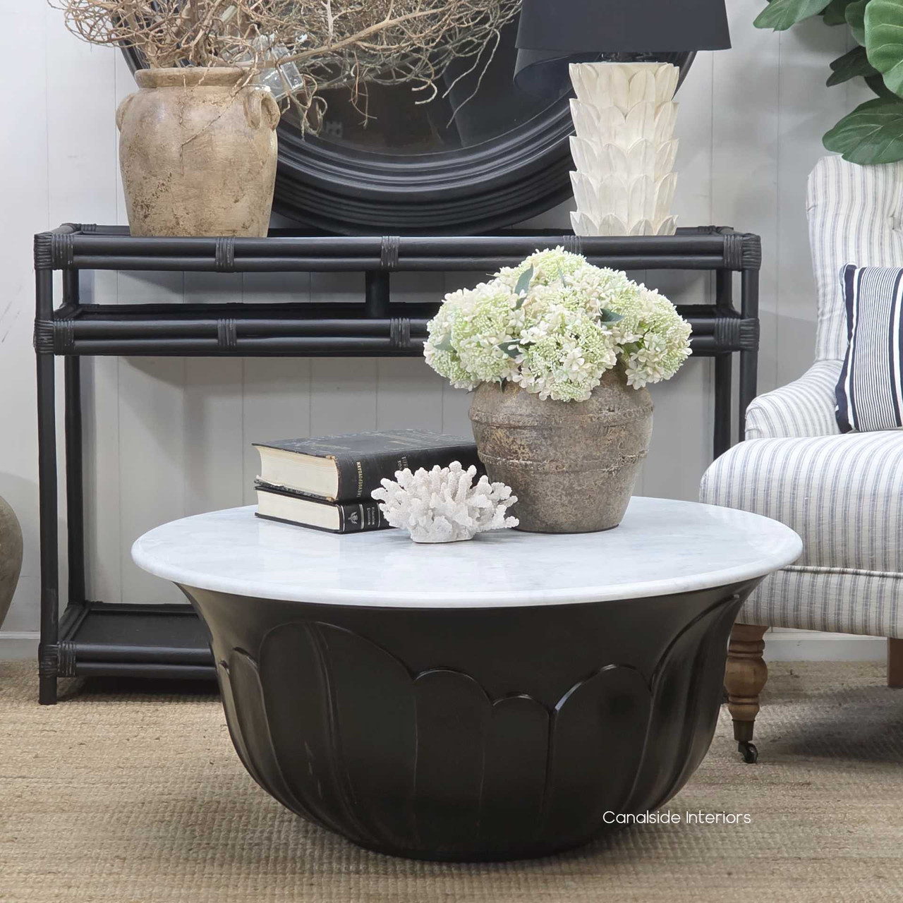 Side profile of the coffee table showcasing the contrast between the crisp white marble top and the dark sculpted base, revealing the craftsmanship of the carved contours.