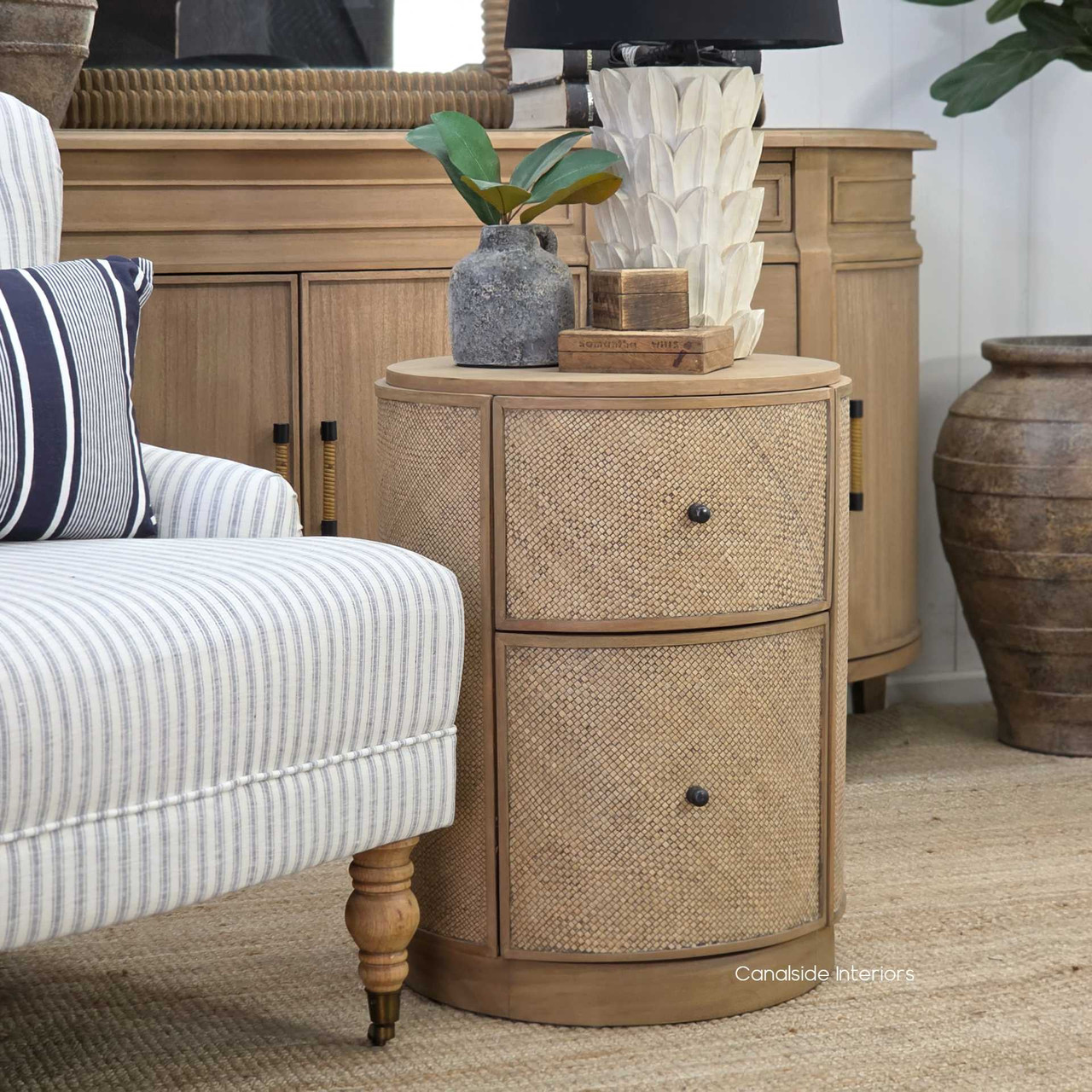 Angled shot of the Langston Rattan Side Table in soft lighting, capturing the warmth and richness of its natural tones.