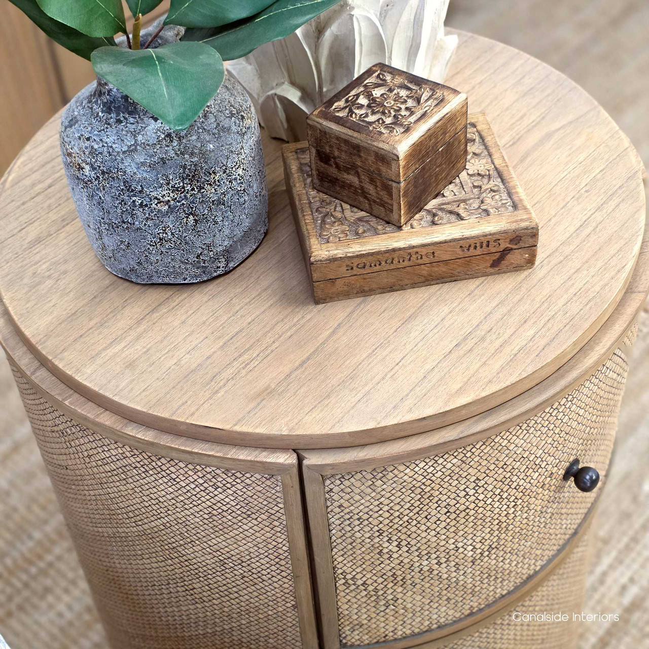 Stacked accessories and décor atop the Langston Rattan Side Table, demonstrating its versatility as a functional yet stylish accent piece.