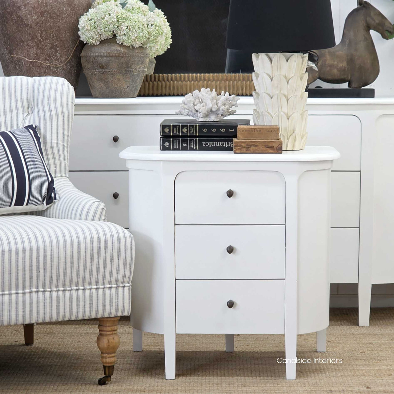 Straight view of the Creemore 3 Drawer Bedside in White, showcasing its curved silhouette, smooth painted finish and simple round hardware.