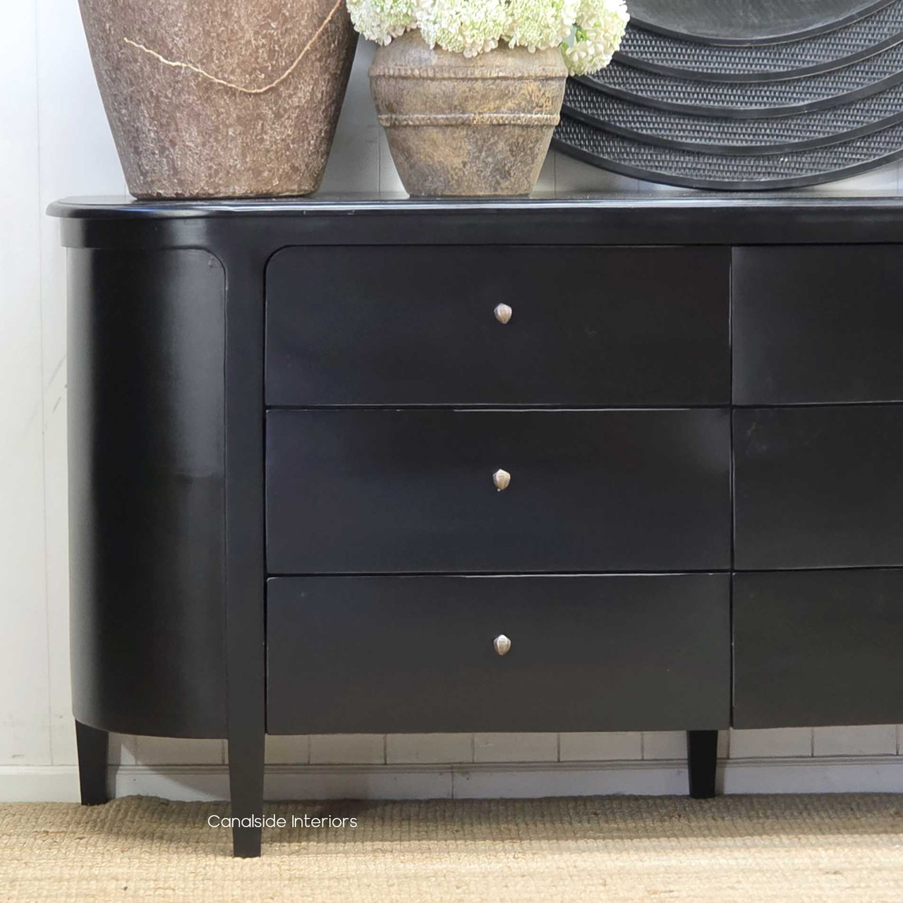 Side angle of the Creemore Chest in Black showing the graceful curve of the body, smooth handcrafted finish, and slim tapered legs for an elevated, contemporary look.