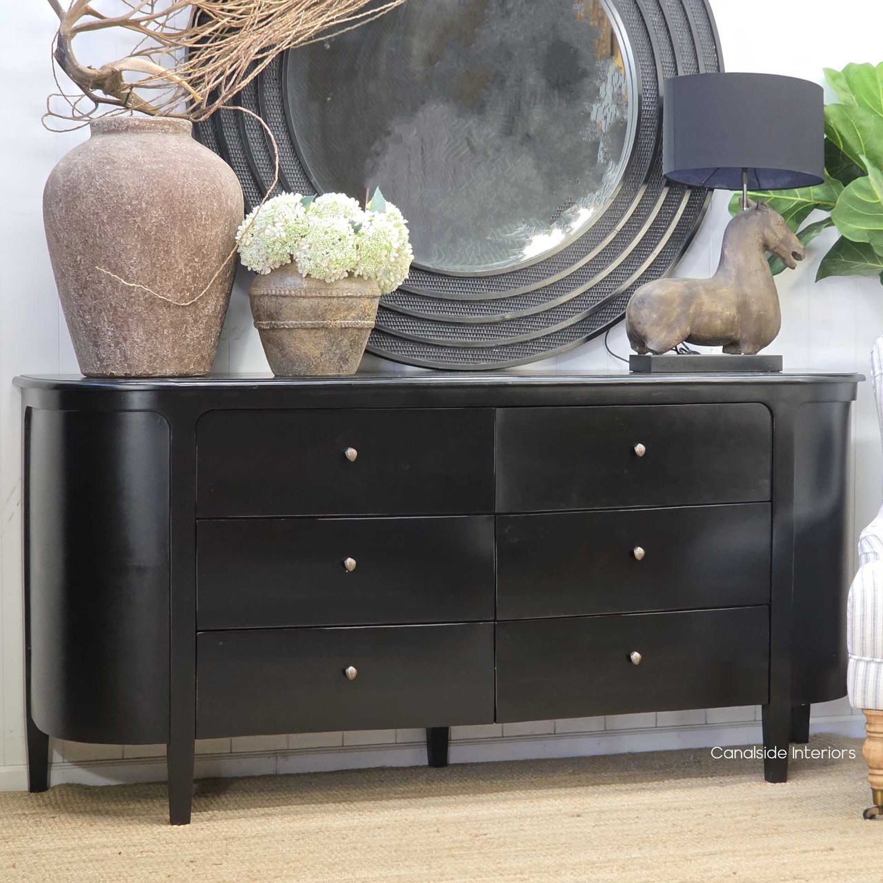 Angled view of the Creemore 6 Drawer Chest in Black highlighting the rounded corner detailing, tapered legs and elegant, understated modern design.