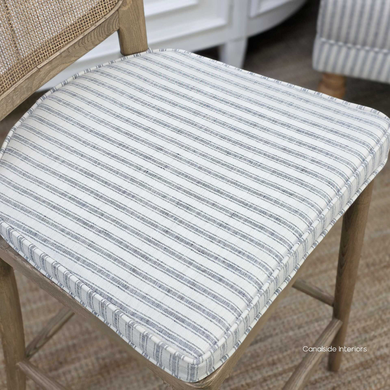 Close-up of the Noda Stool Blue Stripe Cushion in woven ticking fabric, showing the piped edge detail and soft linen-blend texture designed to complement the rattan seat.