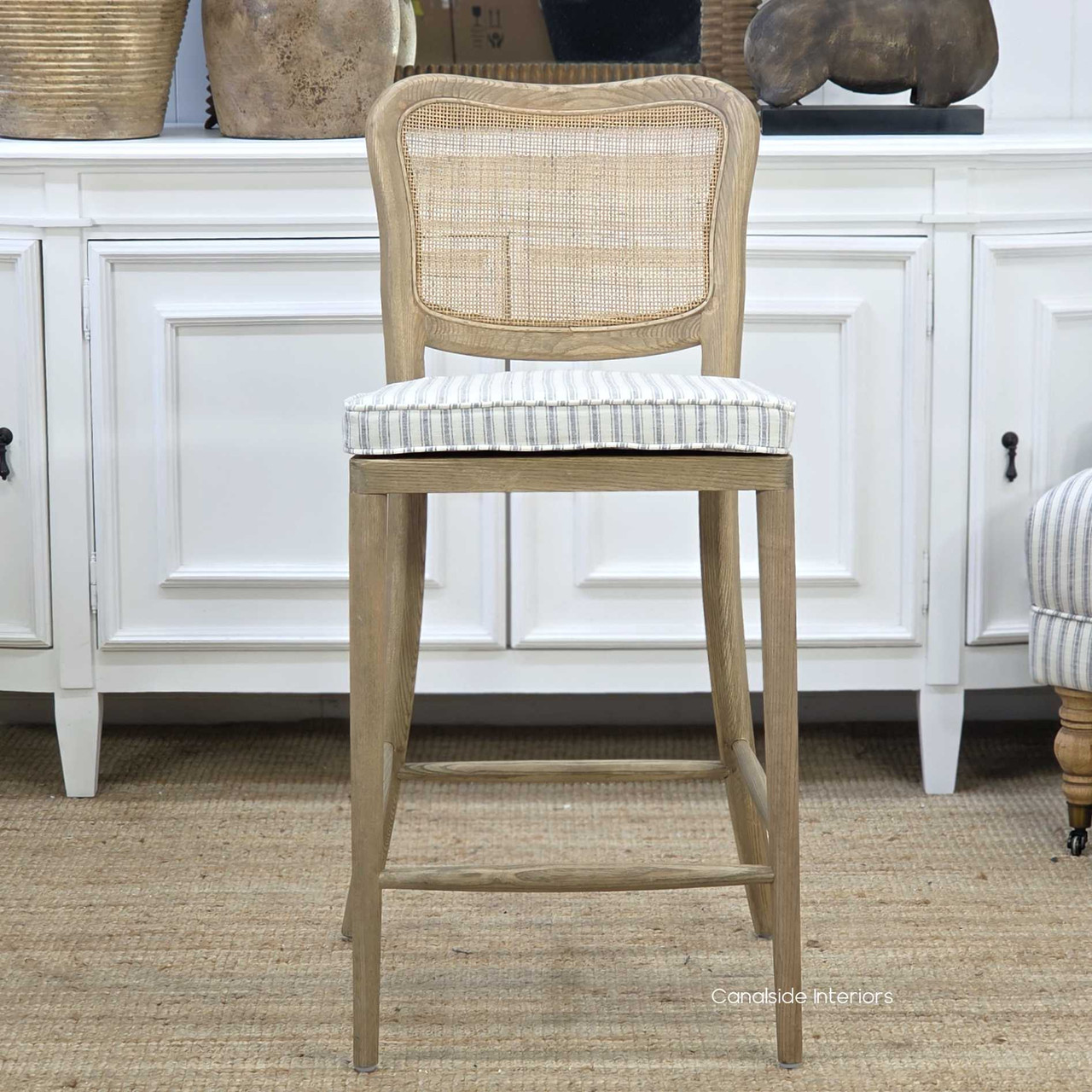 Front view of the Noda Rattan Stool with optional Blue Stripe Cushion, showcasing the classic ticking stripe, shaped seat pad and relaxed coastal styling.