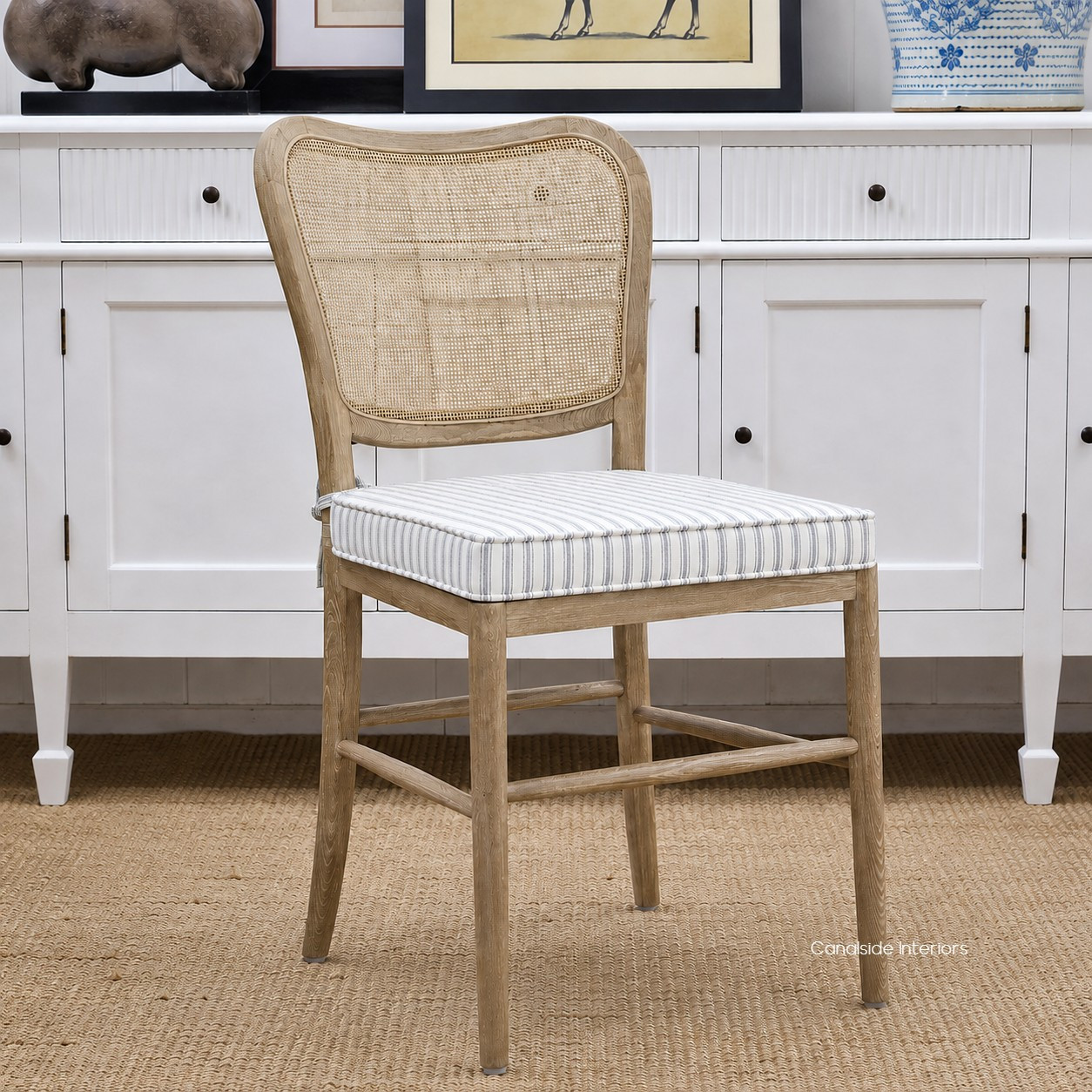 Angled view of the Noda Rattan Chair with Blue Stripe Cushion, highlighting the natural oak frame, woven rattan back and tailored ticking fabric seat.