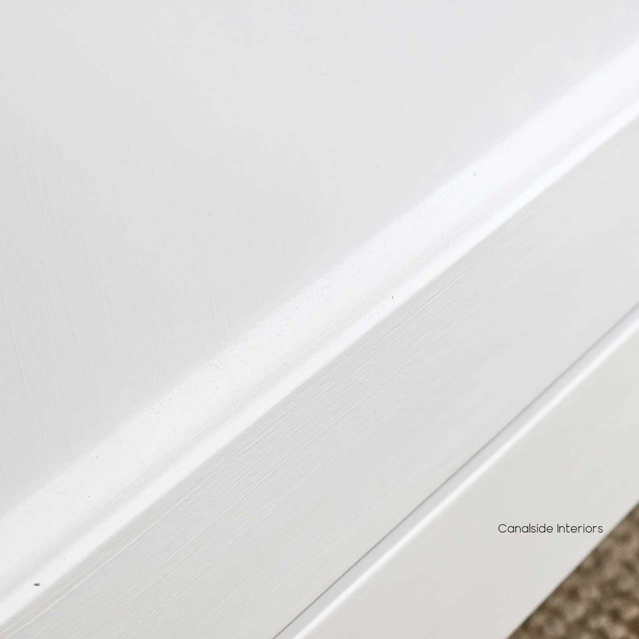 Close-up of the Louis Curved Sideboard’s smooth white finish, showing the delicate paint-stroke texture.