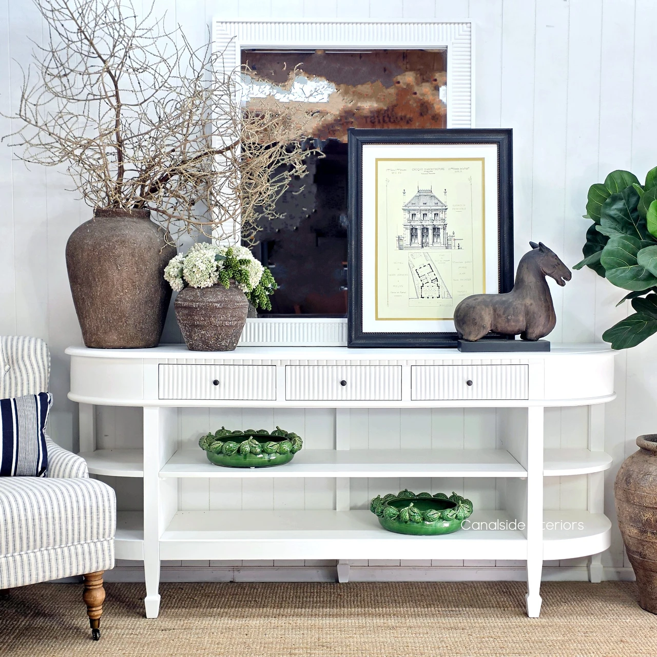 Louis Curved Console Table White styled beside a striped armchair, highlighting its elegant curved end and shelving.