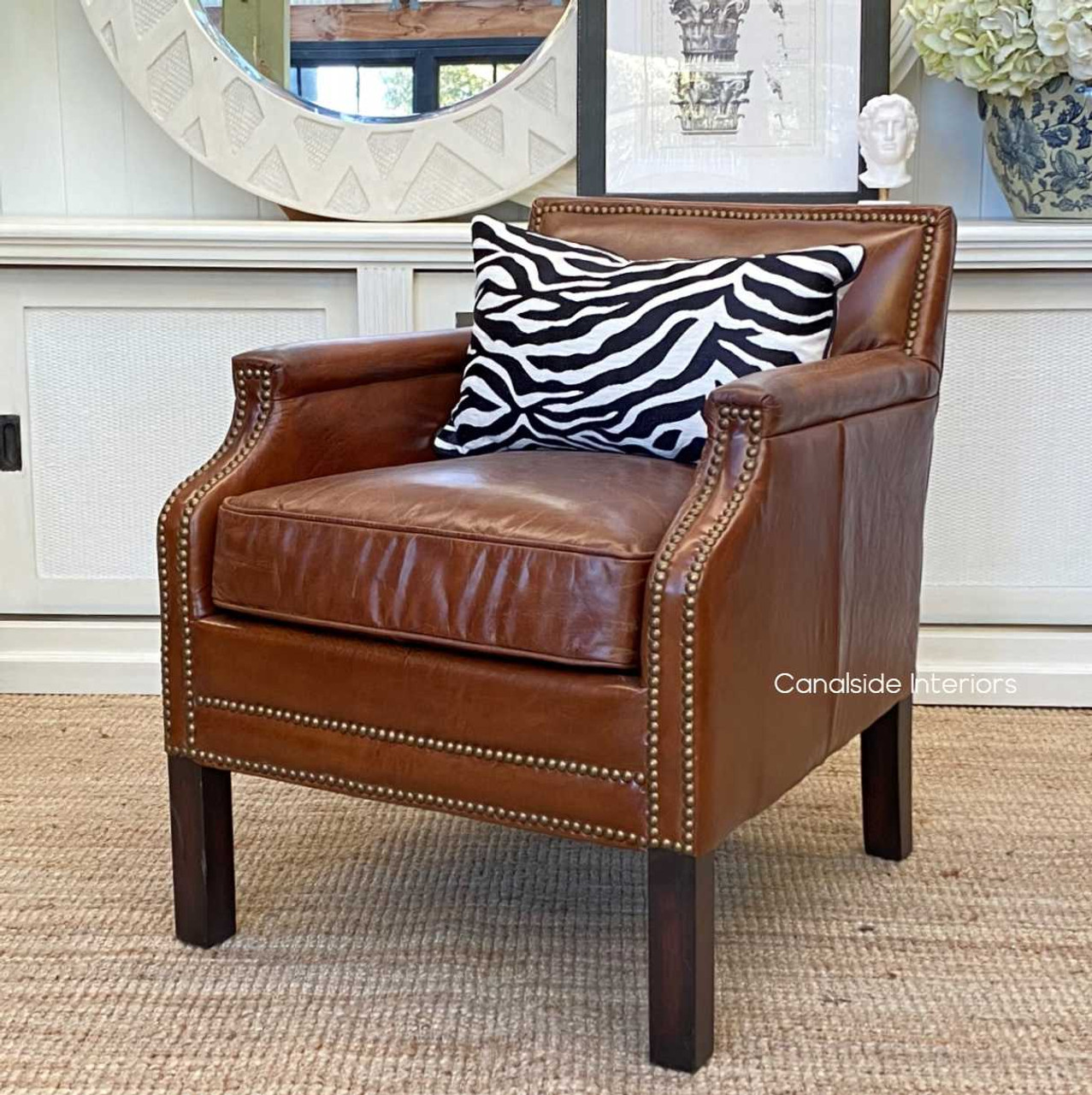 View of the armchair bathed in natural light, accentuating its aged leather's beauty.