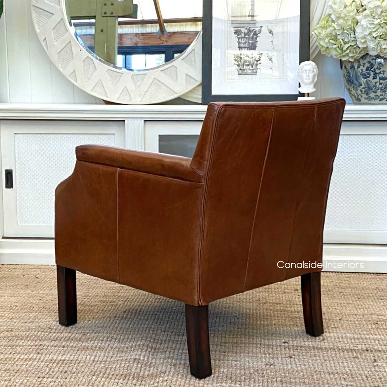 The armchair's rear view, displaying the exquisite detailing and quality of the aged leather.