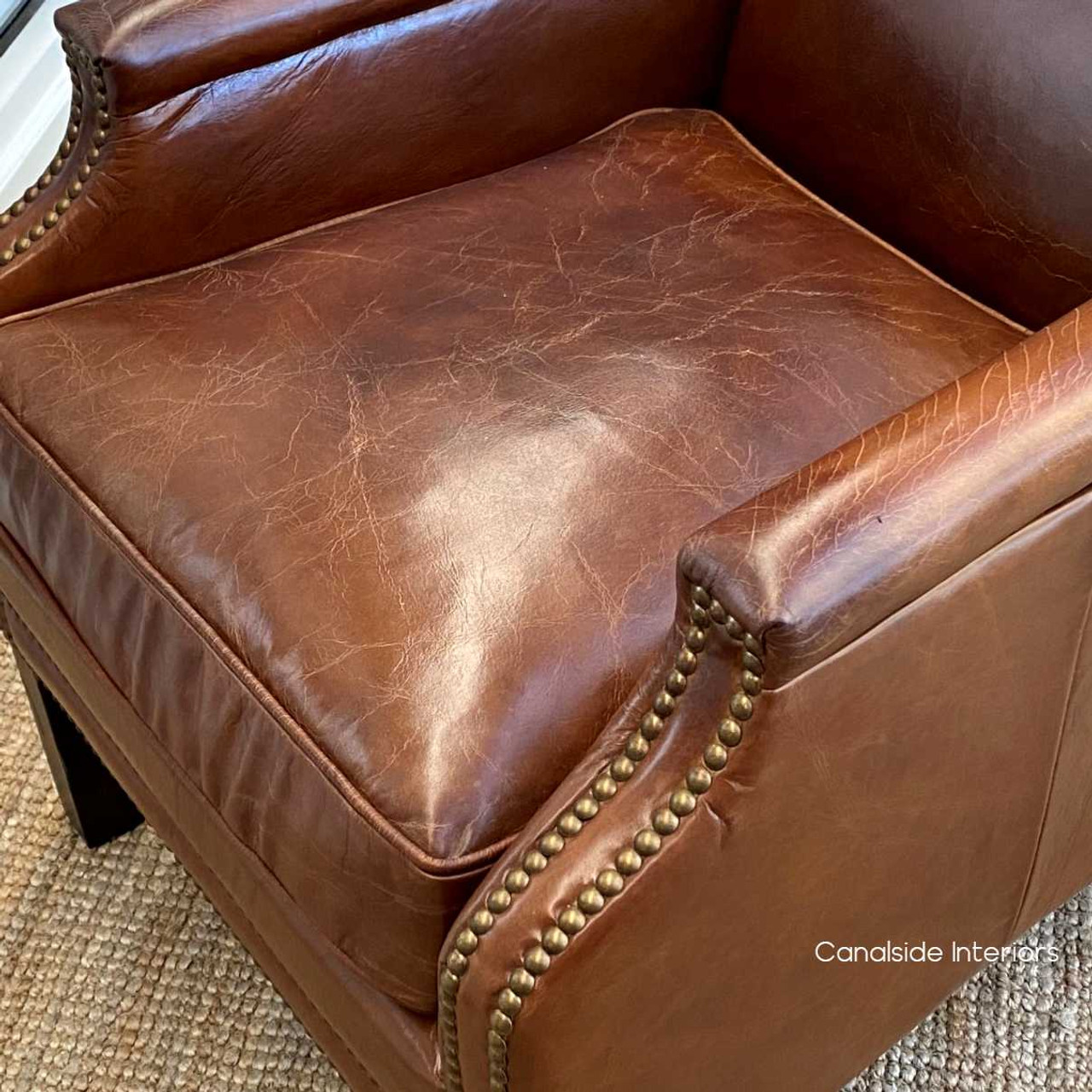 Detailed view of the armchair's craftsmanship, from the stitching to the aged leather finish.
