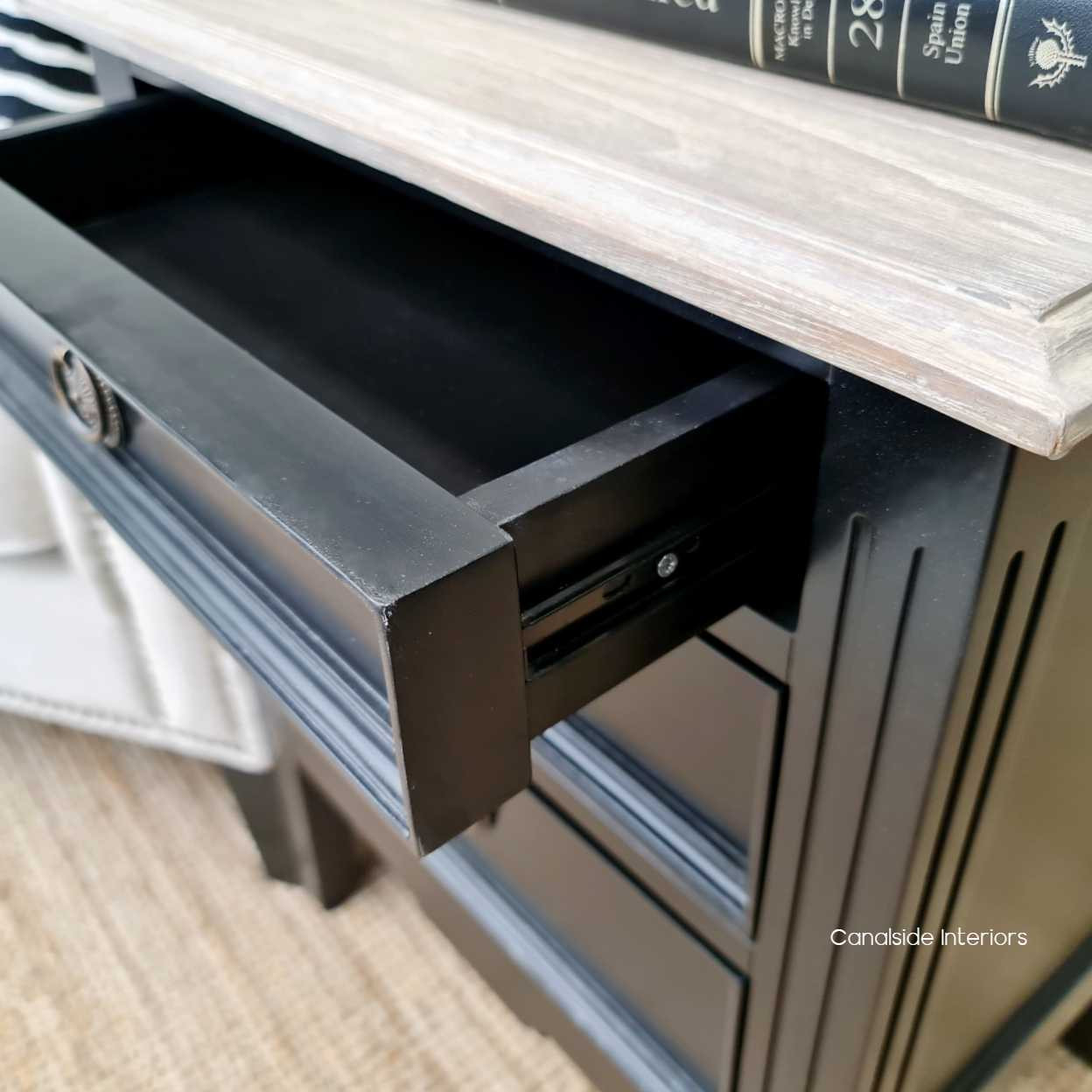 Angled view of the bedside table, displaying its smooth metal runner drawers, combining functionality with style.